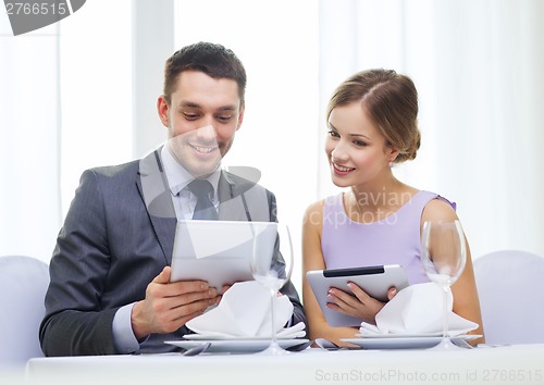 Image of couple with menus on tablet pc at restaurant