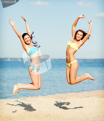 Image of girls in bikini jumping on the beach