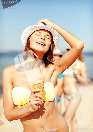 Image of girl in bikini eating ice cream on the beach