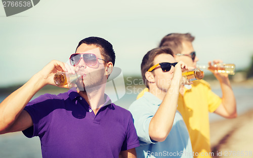 Image of friends on the beach with bottles of drink