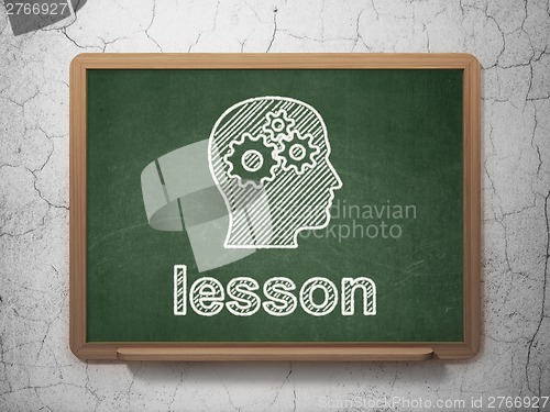 Image of Education concept: Head With Gears and Lesson on chalkboard background