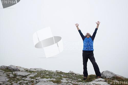 Image of Man spreading hands on mountain peak