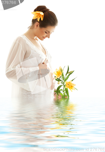 Image of pregnant woman with yellow lily in water