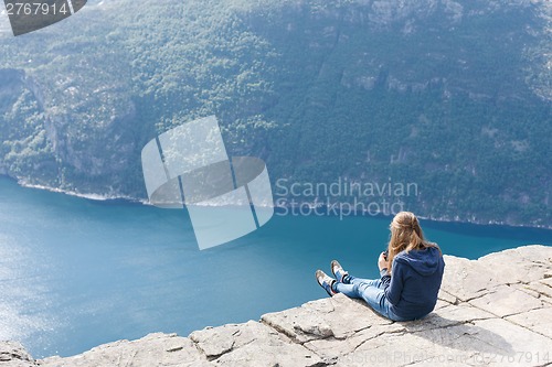 Image of Woman sitting on Pulpit Rock / Preikestolen, Norway