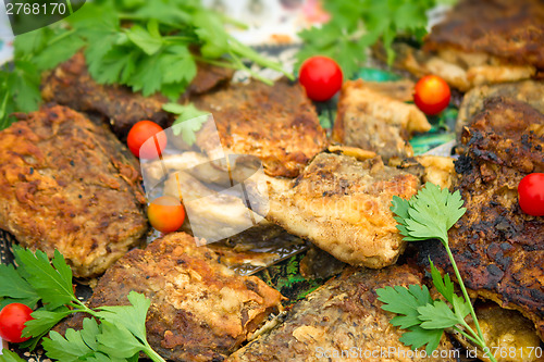 Image of Fried slices of chicken, tomatoes and parsley leaves.