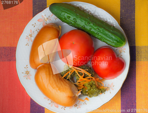 Image of Two big sausages and vegetables on a white dish.