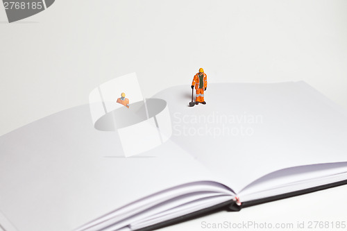 Image of Miniature people in action worker on an open book