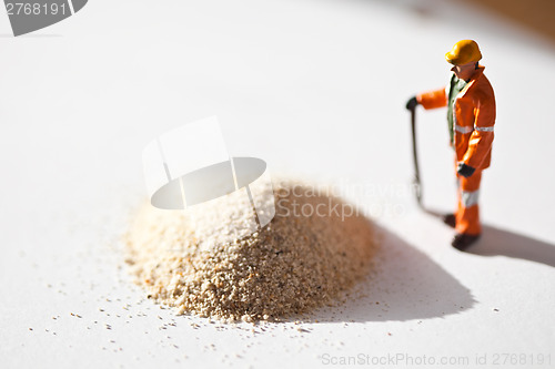 Image of Miniature worker and a stack of sand
