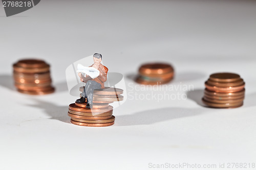 Image of Miniature people sitting on coins