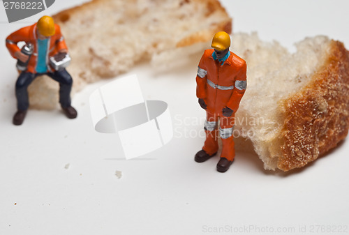 Image of Miniature people in action with a piece of bread