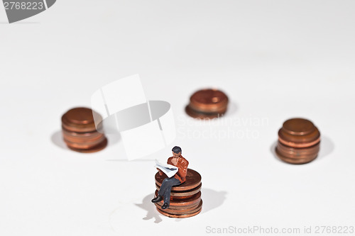 Image of Miniature people sitting on coins