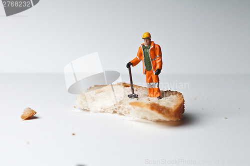 Image of Miniature people in action with a piece of bread