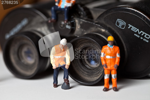 Image of Miniature people in action with magnification glasses