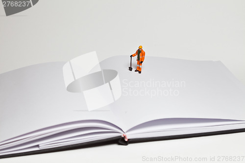 Image of Miniature people in action worker on an open book