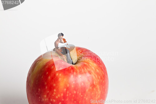 Image of Miniature people in action sitting on an apple