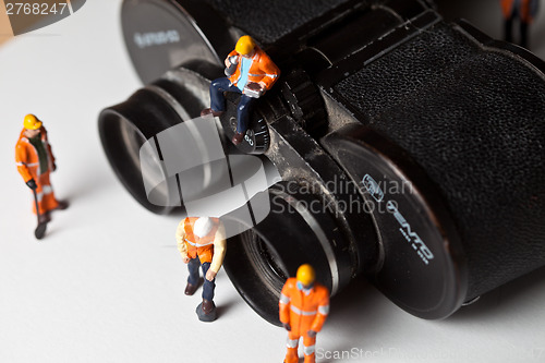 Image of Miniature people in action with magnification glasses