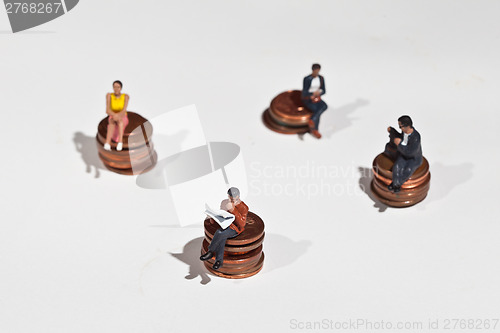 Image of Miniature people sitting on coins