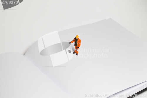 Image of Miniature people in action worker on an open book
