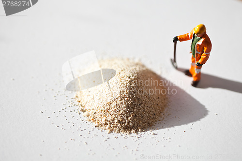 Image of Miniature worker and a stack of sand