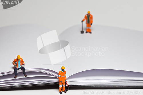 Image of Miniature people in action worker on an open book
