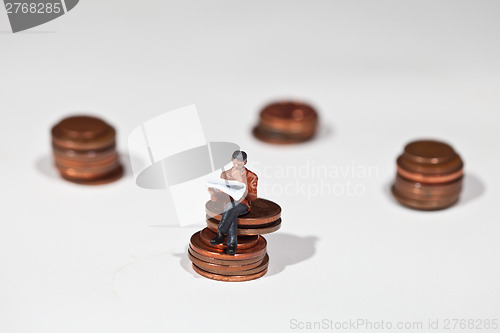 Image of Miniature people sitting on coins