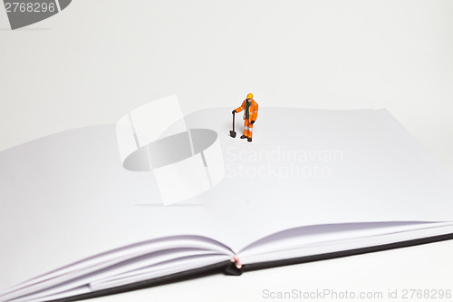 Image of Miniature people in action worker on an open book