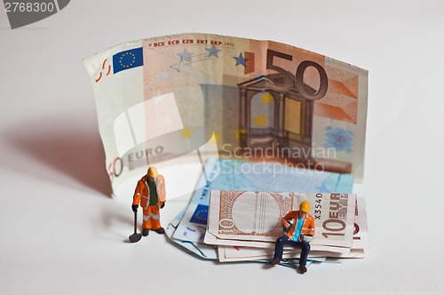 Image of Miniature people in action with euro banknotes