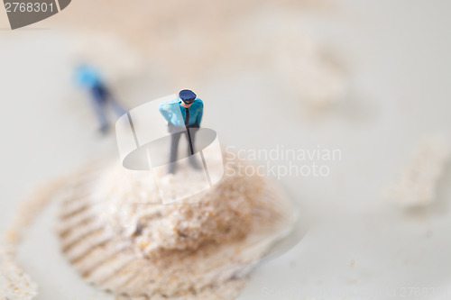 Image of Miniature policeman on a stack of sand while one is lying dead i