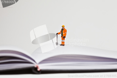 Image of Miniature people in action worker on an open book