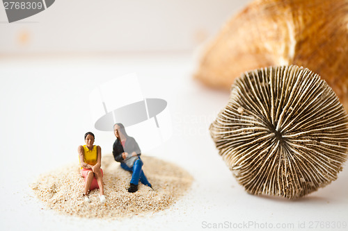 Image of Miniature people sitting on a stack of sand
