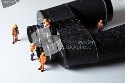 Image of Miniature people in action with magnification glasses