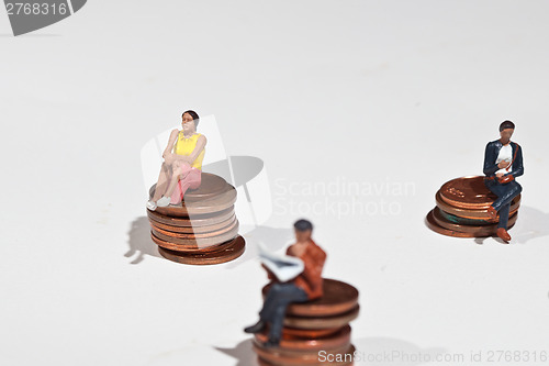 Image of Miniature people sitting on coins