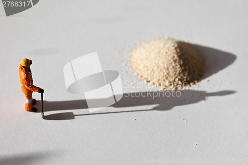 Image of Miniature worker and a stack of sand