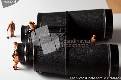 Image of Miniature people in action with magnification glasses