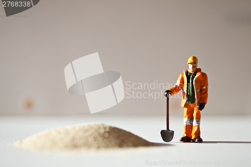 Image of Miniature worker and a stack of sand