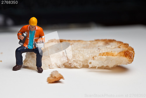 Image of Miniature people in action with a piece of bread