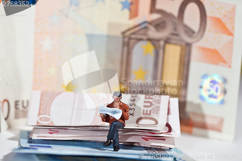 Image of Miniature people in action with euro banknotes