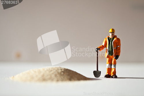 Image of Miniature worker and a stack of sand