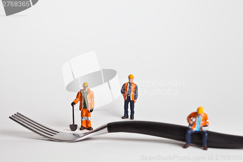 Image of Miniature people in action worker on a fork