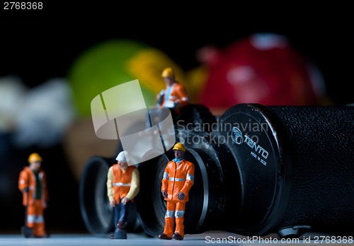 Image of Miniature people in action with magnification glasses