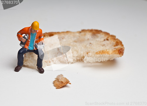 Image of Miniature people in action with a piece of bread