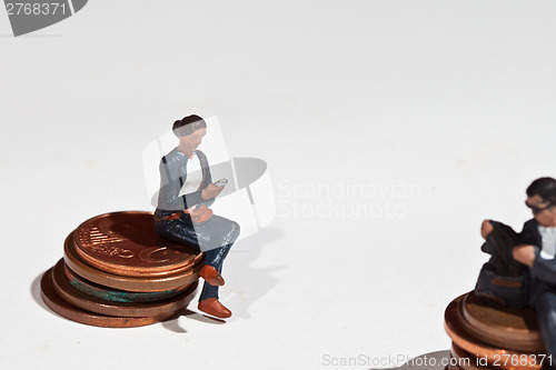Image of Miniature people sitting on coins