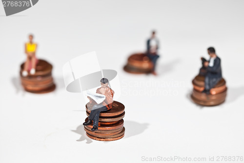 Image of Miniature people sitting on coins