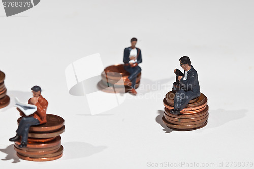 Image of Miniature people sitting on coins