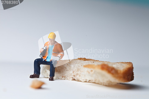 Image of Miniature people in action with a piece of bread