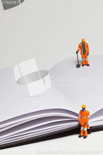 Image of Miniature people in action worker on an open book