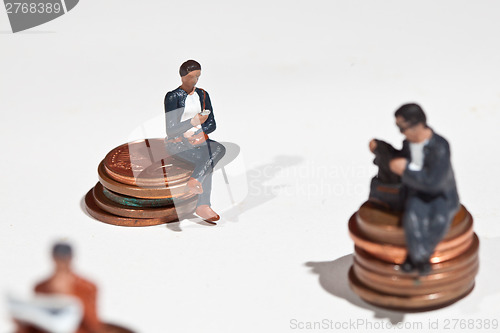 Image of Miniature people sitting on coins