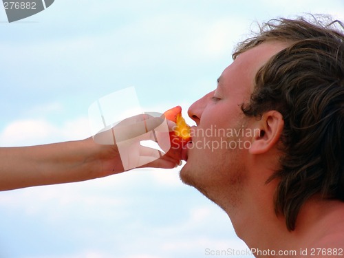 Image of The female hand feeds the guy with a peach