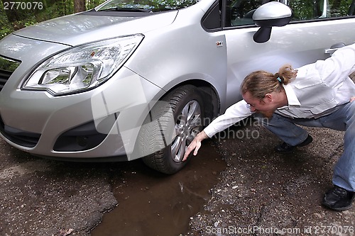 Image of Upset driver man in front of automobile watching damaged car of 