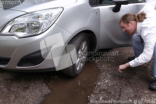 Image of Upset driver man in front of automobile watching damaged car of 